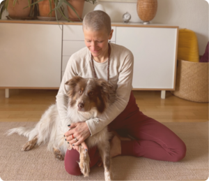 Yoga teacher(Carly Snedeker) sitting and hugging dog in modern interior